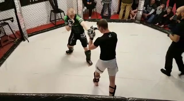 Zwei Sportler im Schlagabtausch im MMA-Käfig.