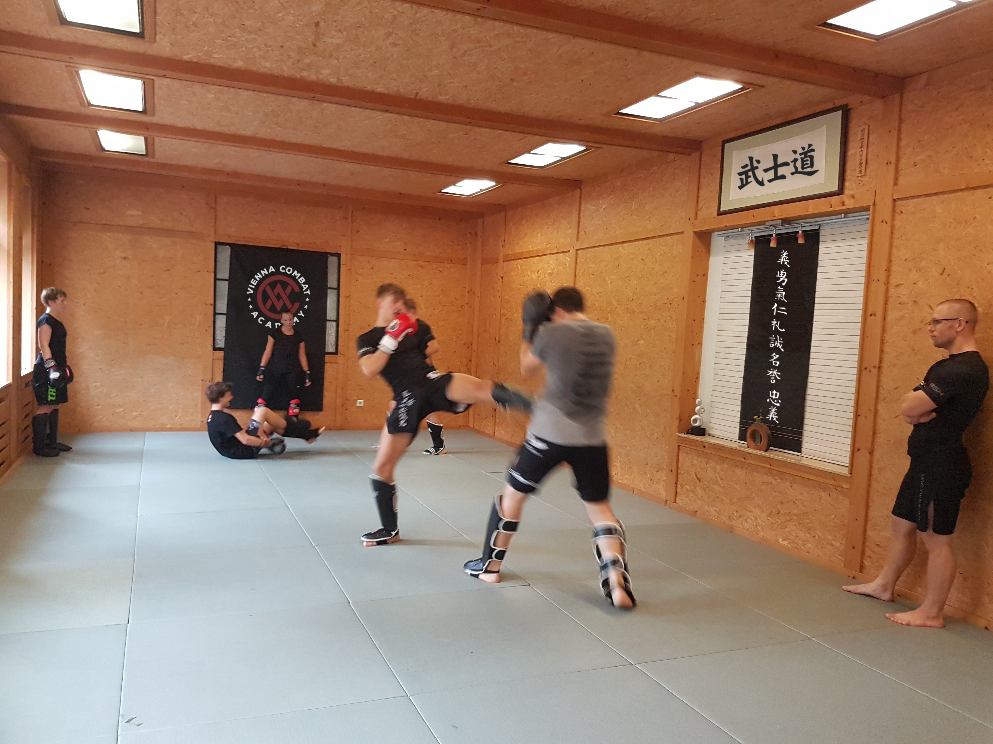 Trainierende üben Kickboxtechniken in Paaren.
