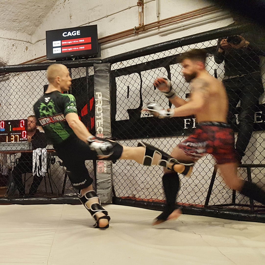 Zwei Sportler im MMA-Kampf am Käfig.